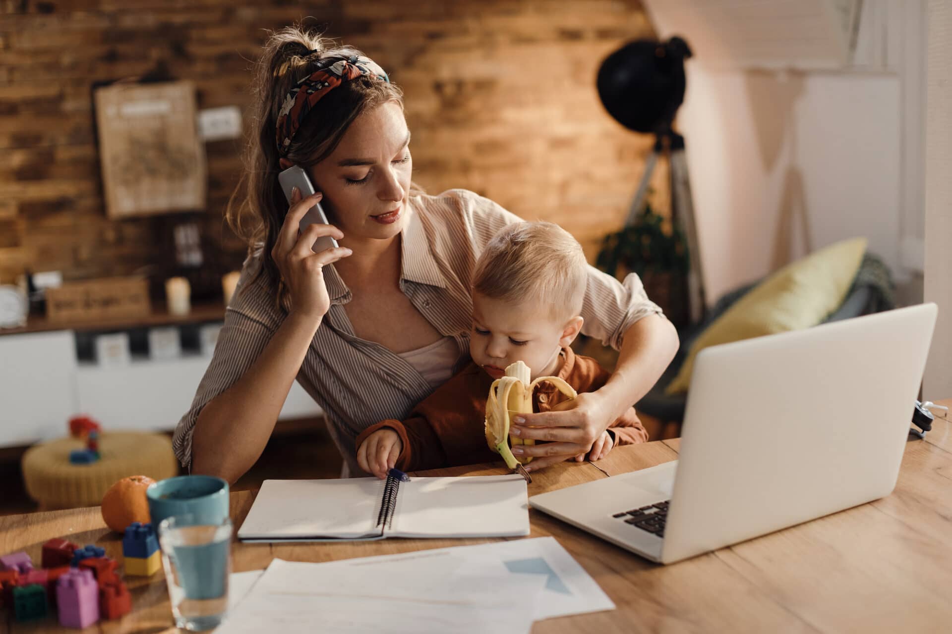 Busy mom feeding her son while working from home and working on a side hustle. 